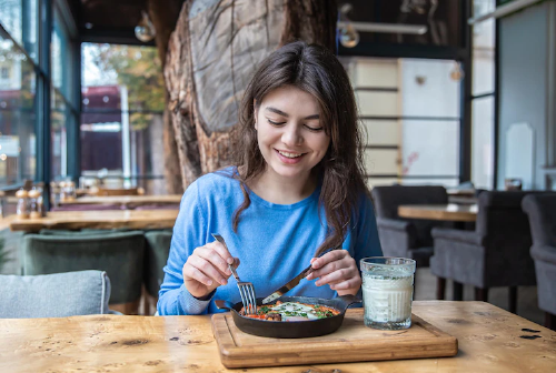image young woman having a meal at a wooden table