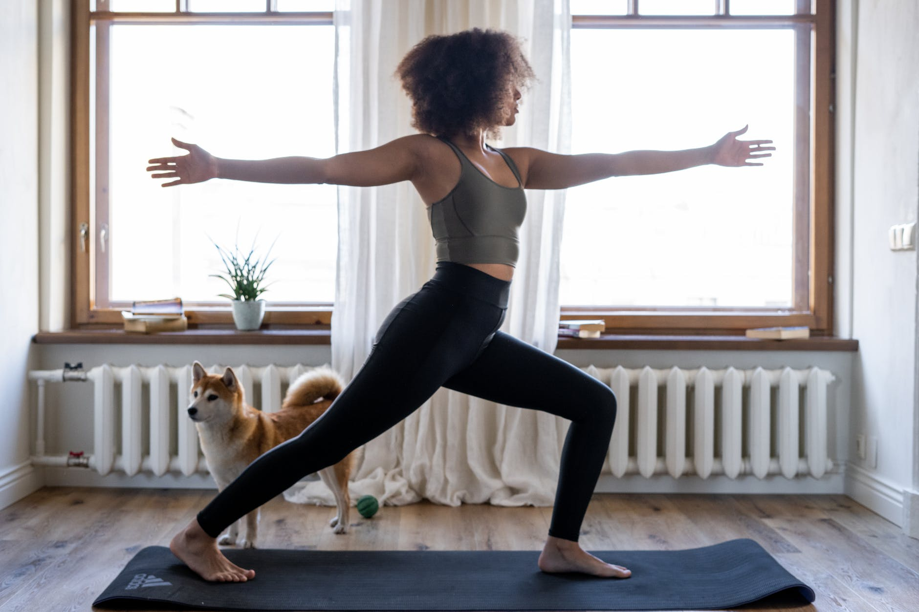 afroamerican woman practicing yoga at home with her dog