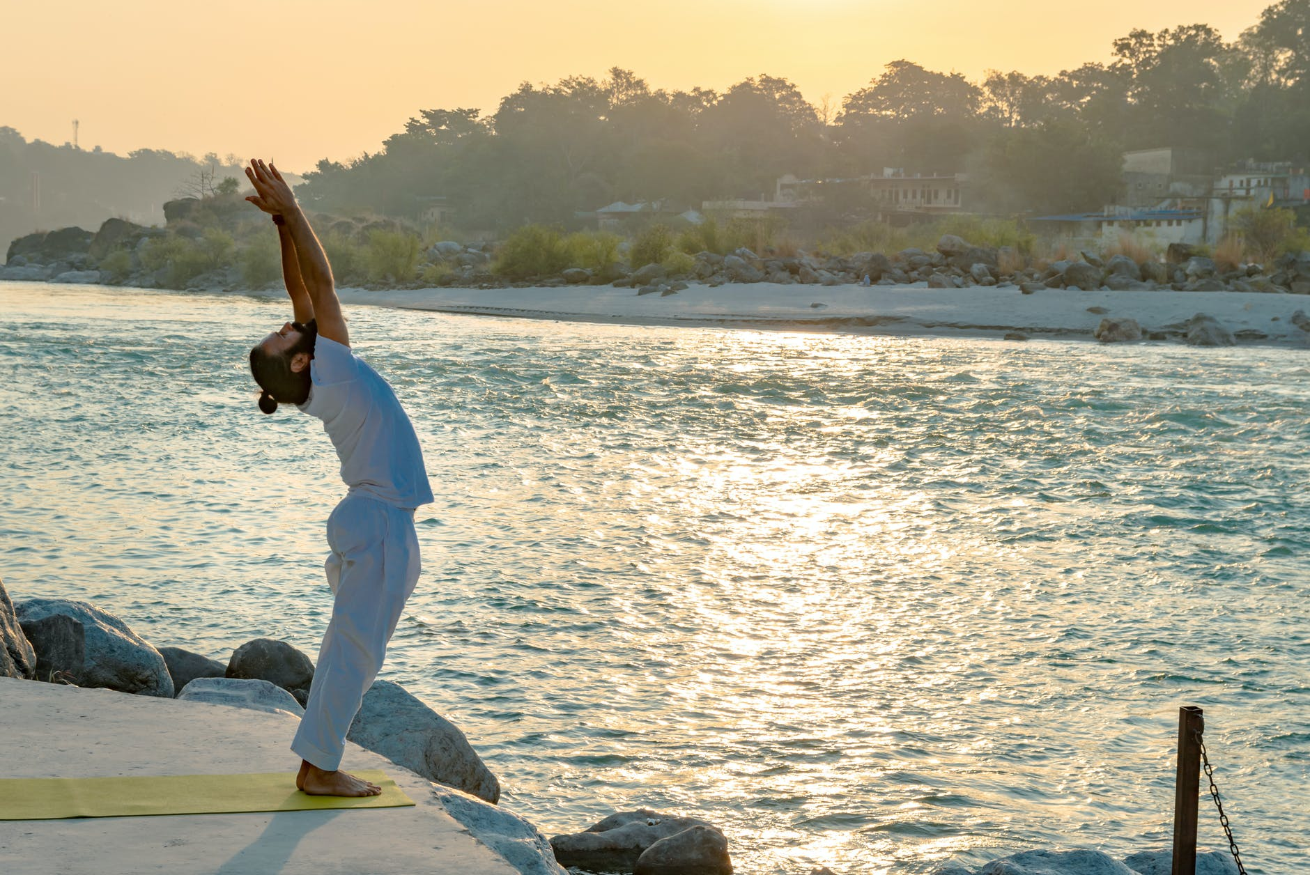 man in white t-shirt and pants doing the sun salutation