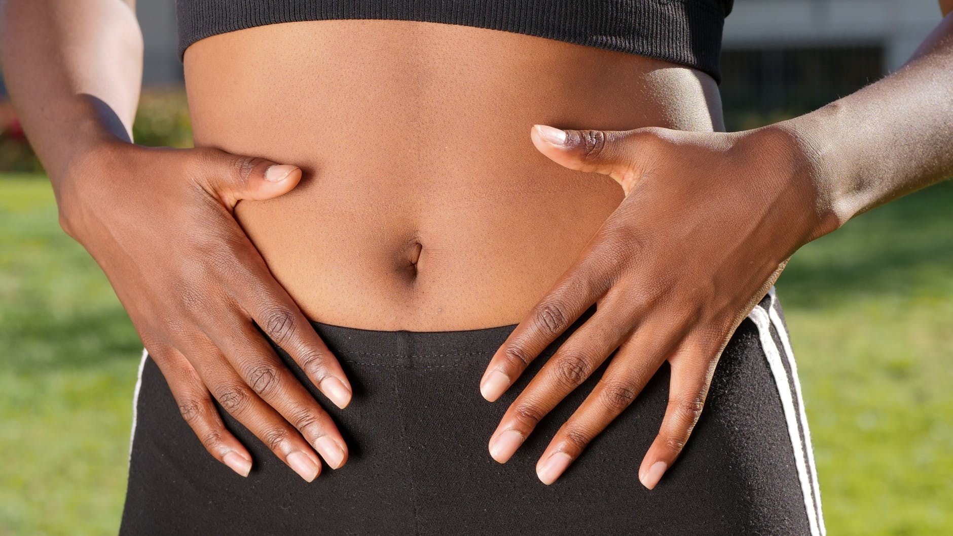 black woman with both hands on their belly