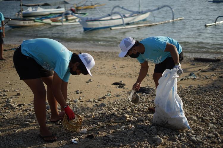 Two young people picking trash from a beach