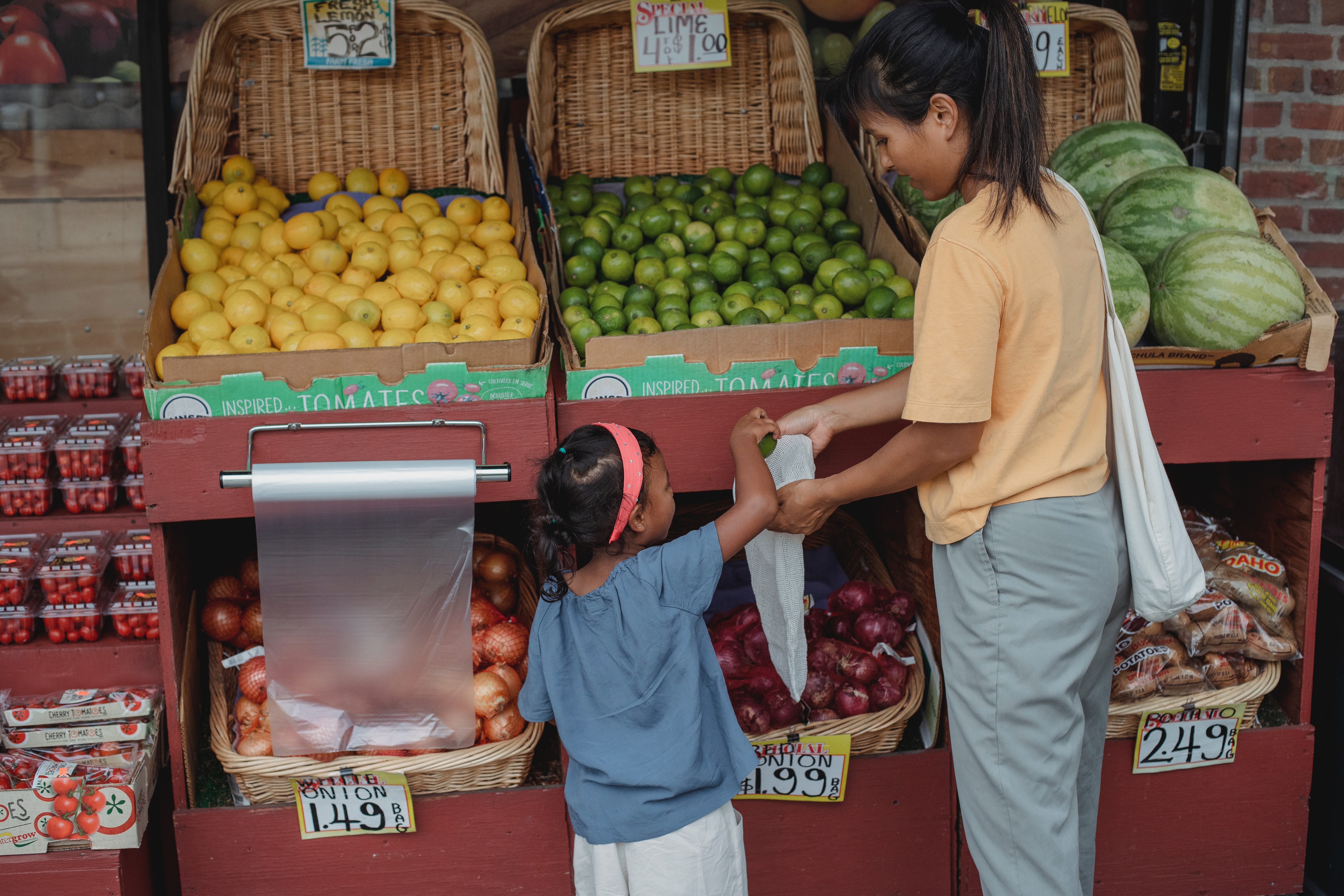 A little girl and her mom shopping in a fruit market