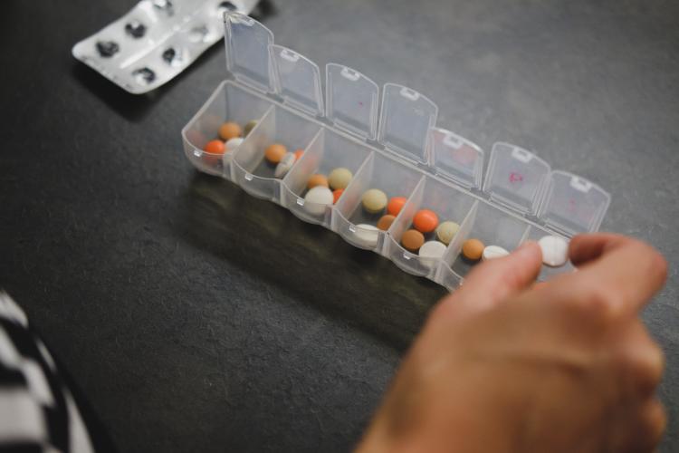 a case filled with pills and a hand grabbing one