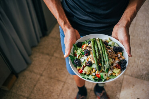 man holding a bowl full of fresh food