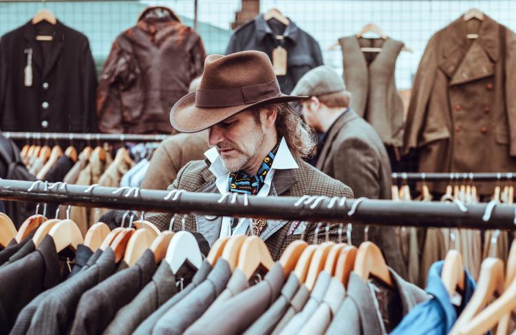Man in a cowboy hat shopping second-hand clothes