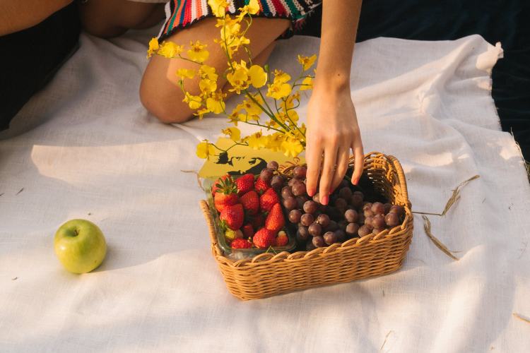 image ethnic woman picking fruit from a rectangular brown wicker basket