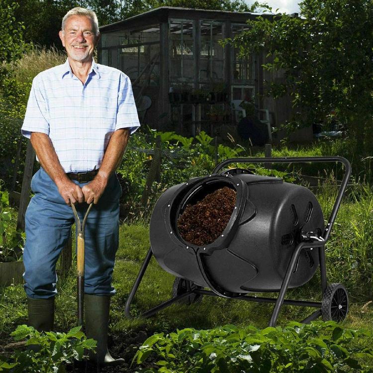 Man in his garden with the compost tumbler 