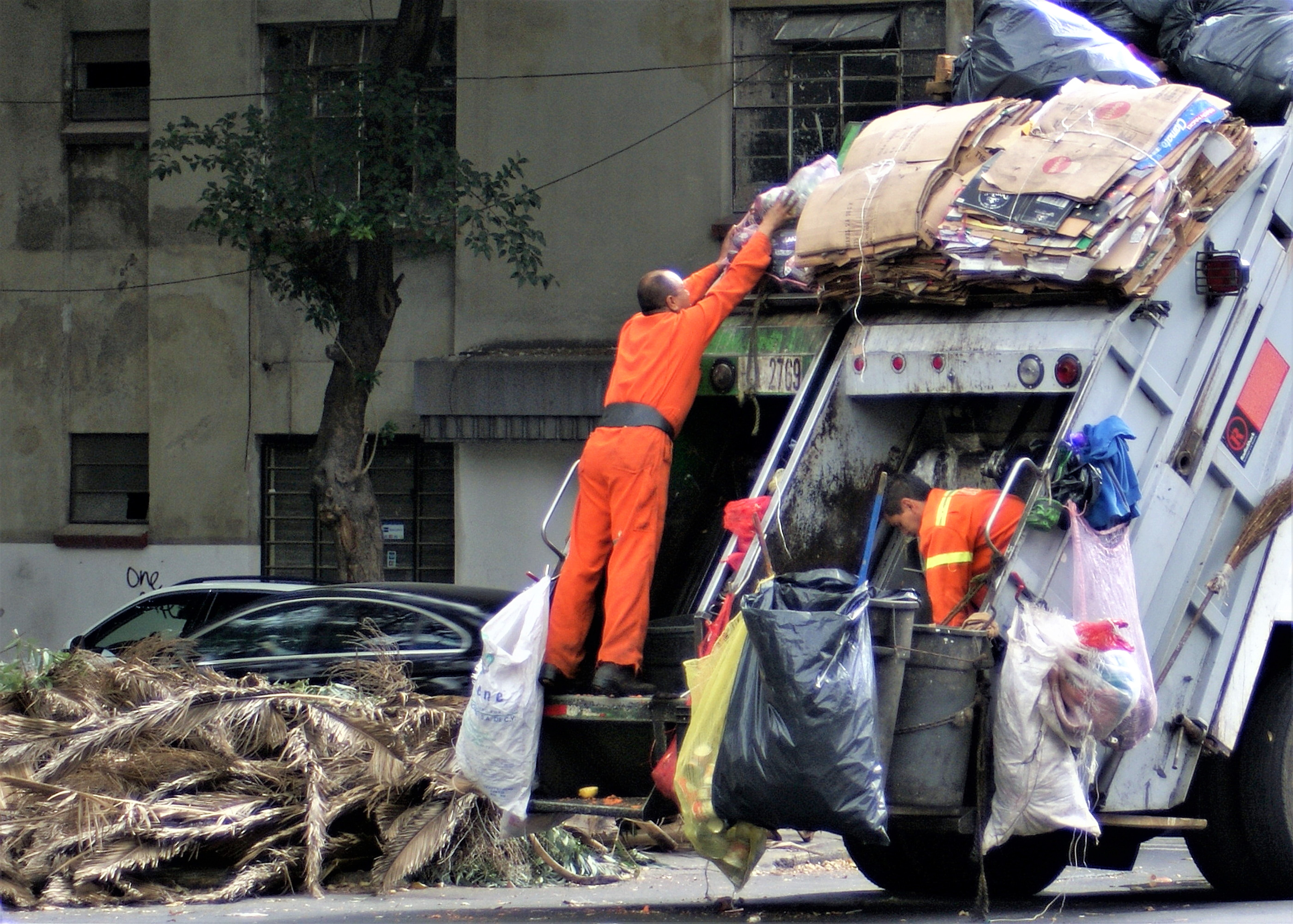 municipal workers lifting garbage on a truck