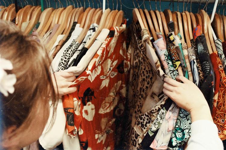 Woman looking at clothes There\'s a woman touching and looking at some clothes on a rail.